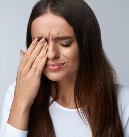 A woman with blurry vision holds her hand to her head.