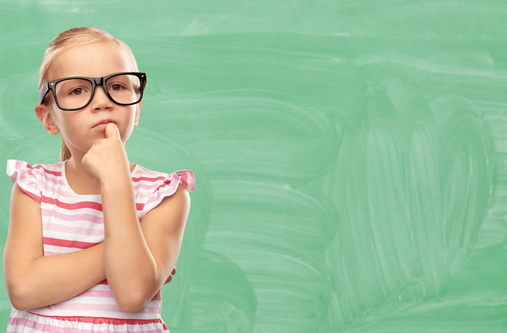 A young girl wearing glasses for myopia control against a chalkboard like background