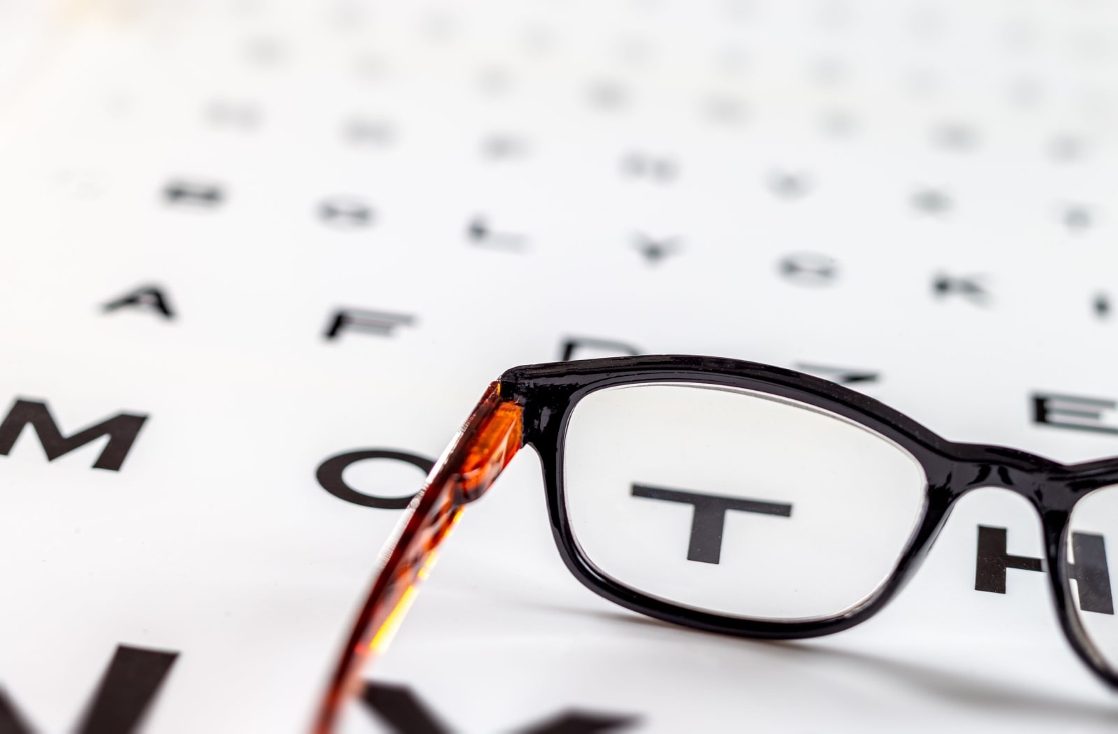 A pair of glasses sitting on a Snellen eye chart
