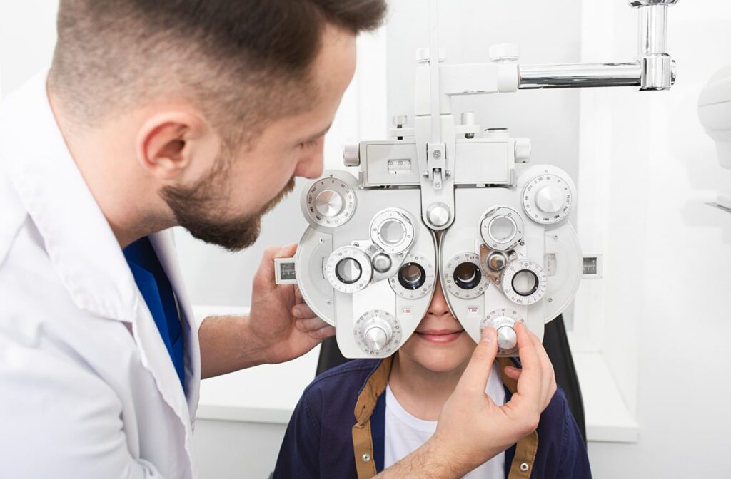 A male optometrist uses a phoropter to examine a child's eyes