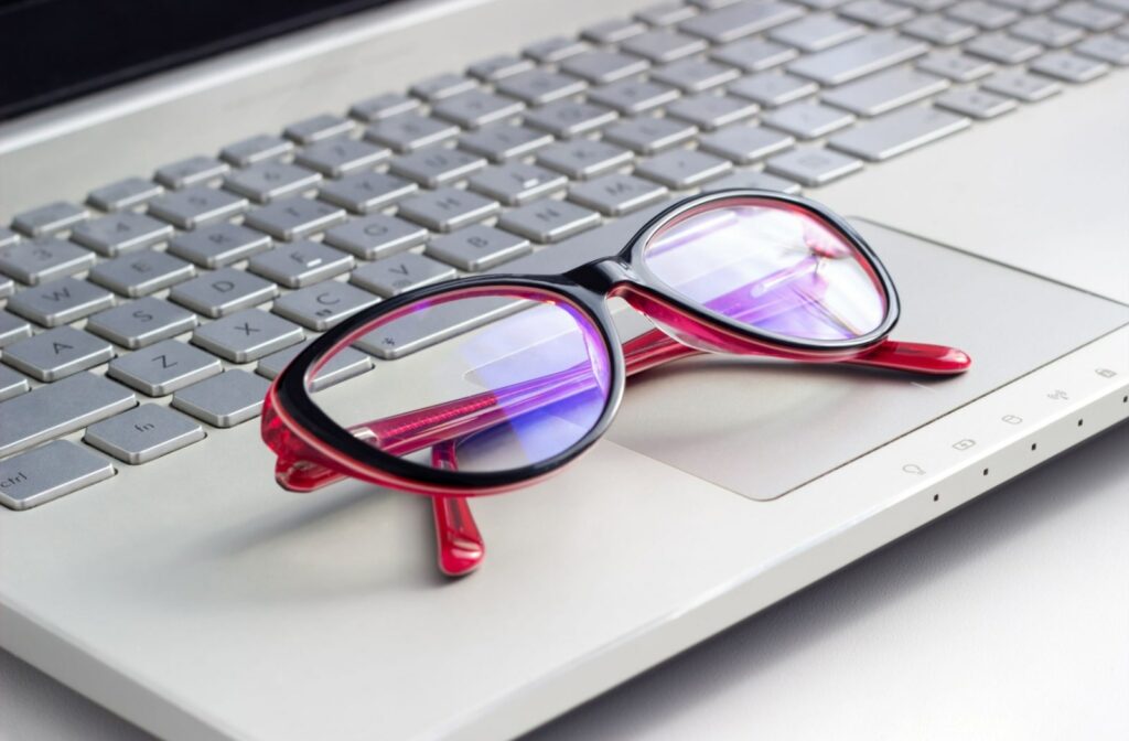 A close-up of a pair of glasses with a blue light filter on a laptop.