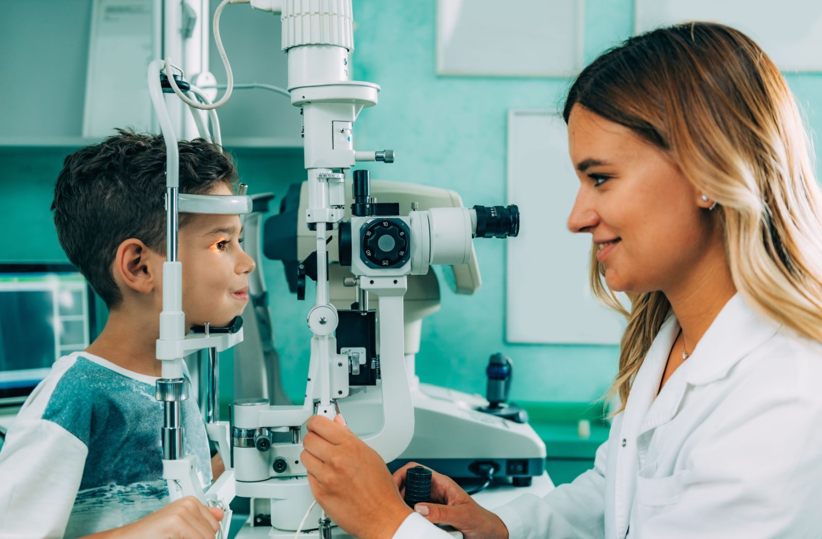 A female optometrist examines a young boy's eyes with a slit lamp