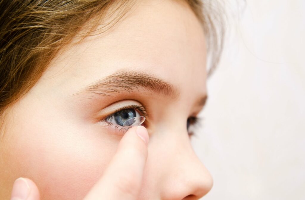 A close up of a child inserting a contact lens
