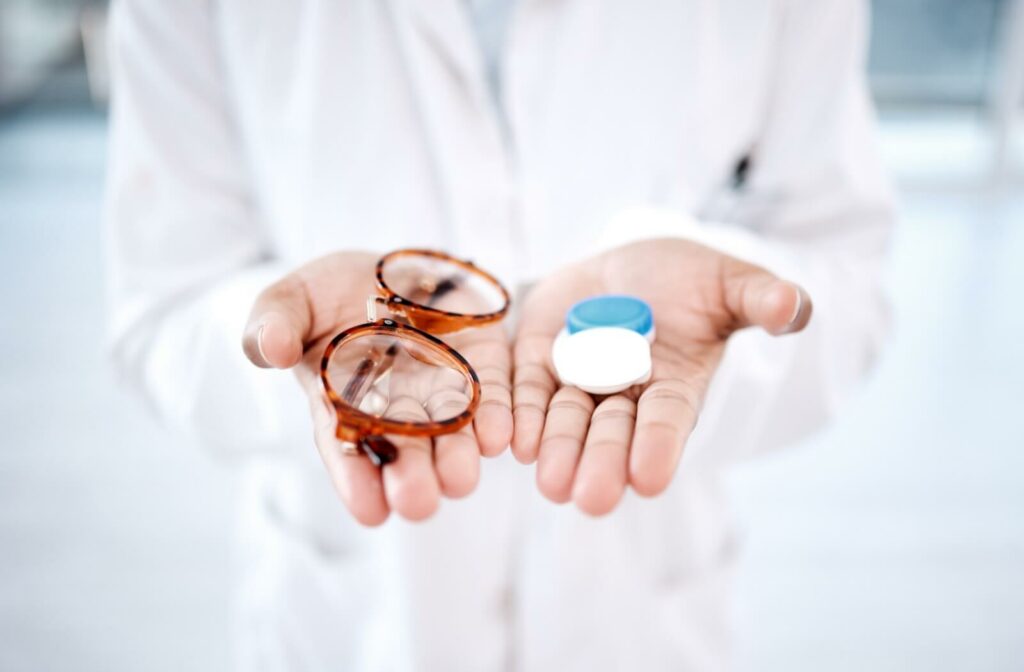 Someone holds a pair of glasses and a contact lens case on each hand.