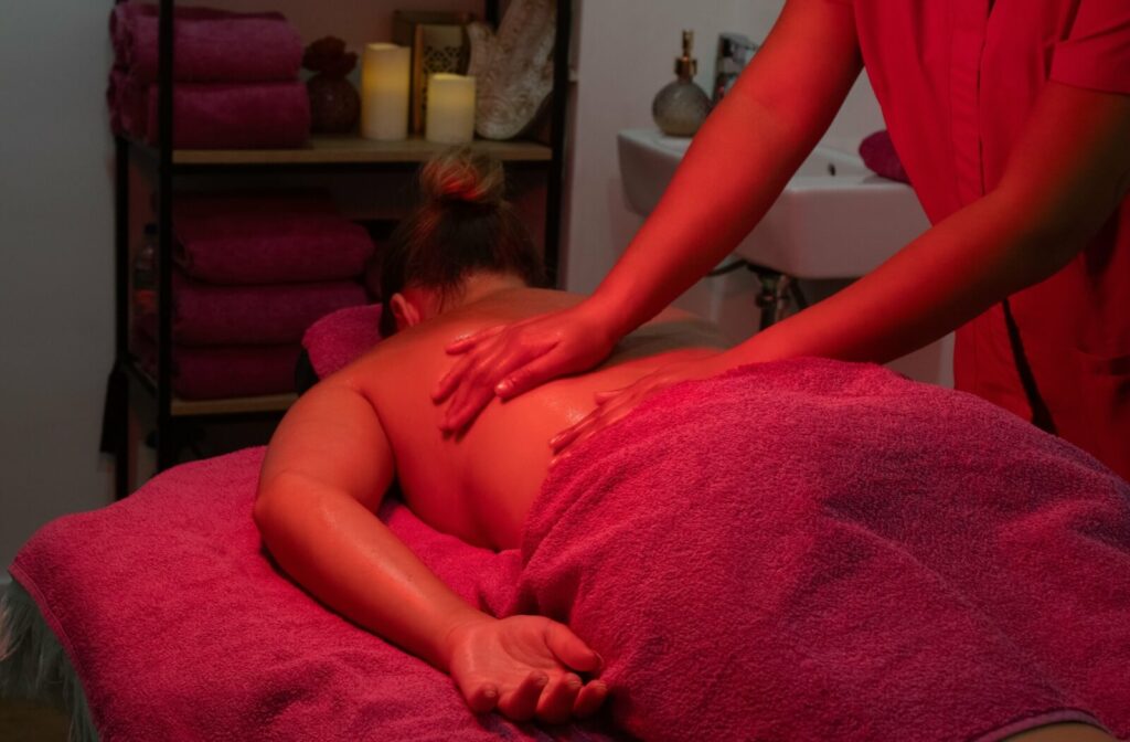 A person receiving a relaxing back massage enhanced with red light therapy in a calming spa setting