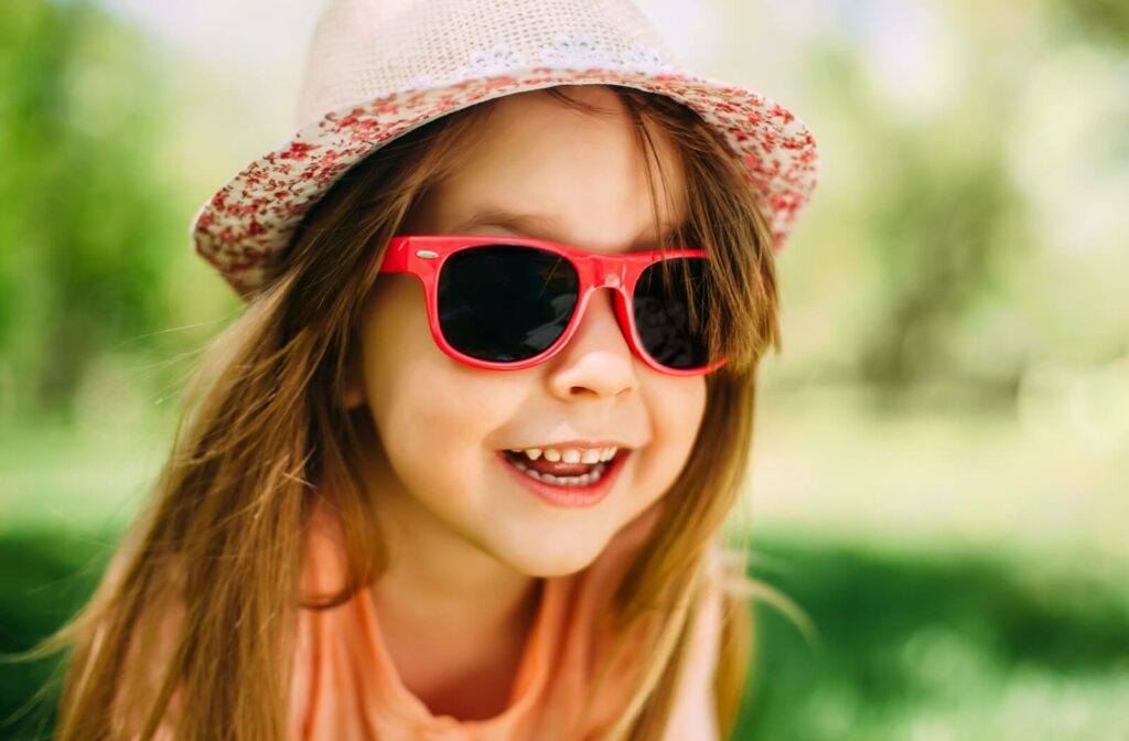 An image of a child wearing a hat and sunglasses playing outside.