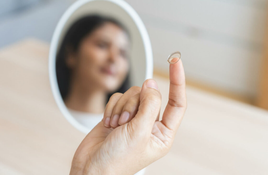 A contact lens rests on a person's pointer finger as they prepare to insert a soft contact lens.