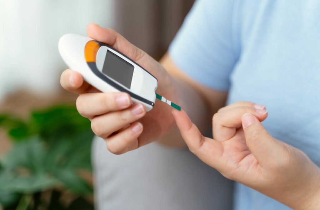Close-up of a person using a device with a lancet to check blood sugar levels by poking their fingertip.